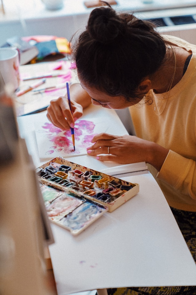 a woman painting a canvas with a paintbrush